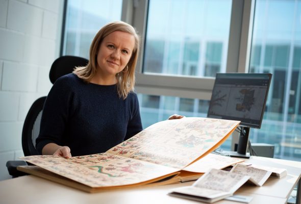 Dr Agnieszka Brylak at her desk with a facsimile of a pre-Hispanic codex.