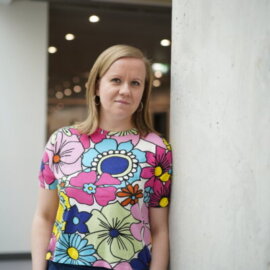 Agnieszka Brylak está en el interior, junto a un pilar de hormigón en un espacio moderno.