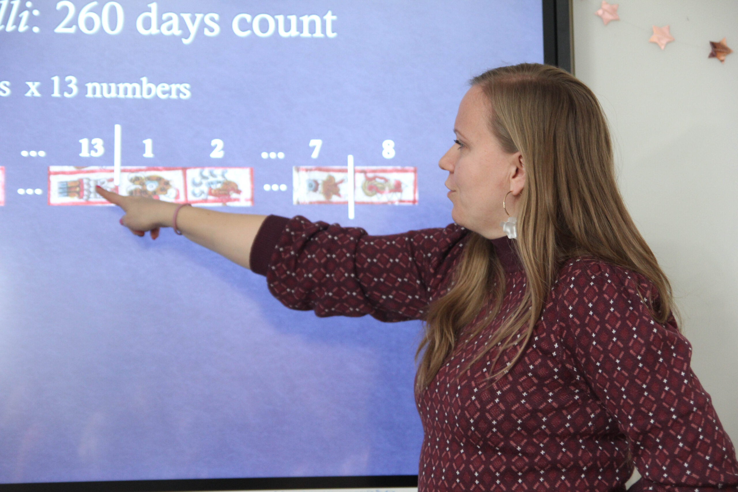 Dr Agieszka Brylak wskazuje na fragment azteckiego kalendarza wyświetlany na ekranie.