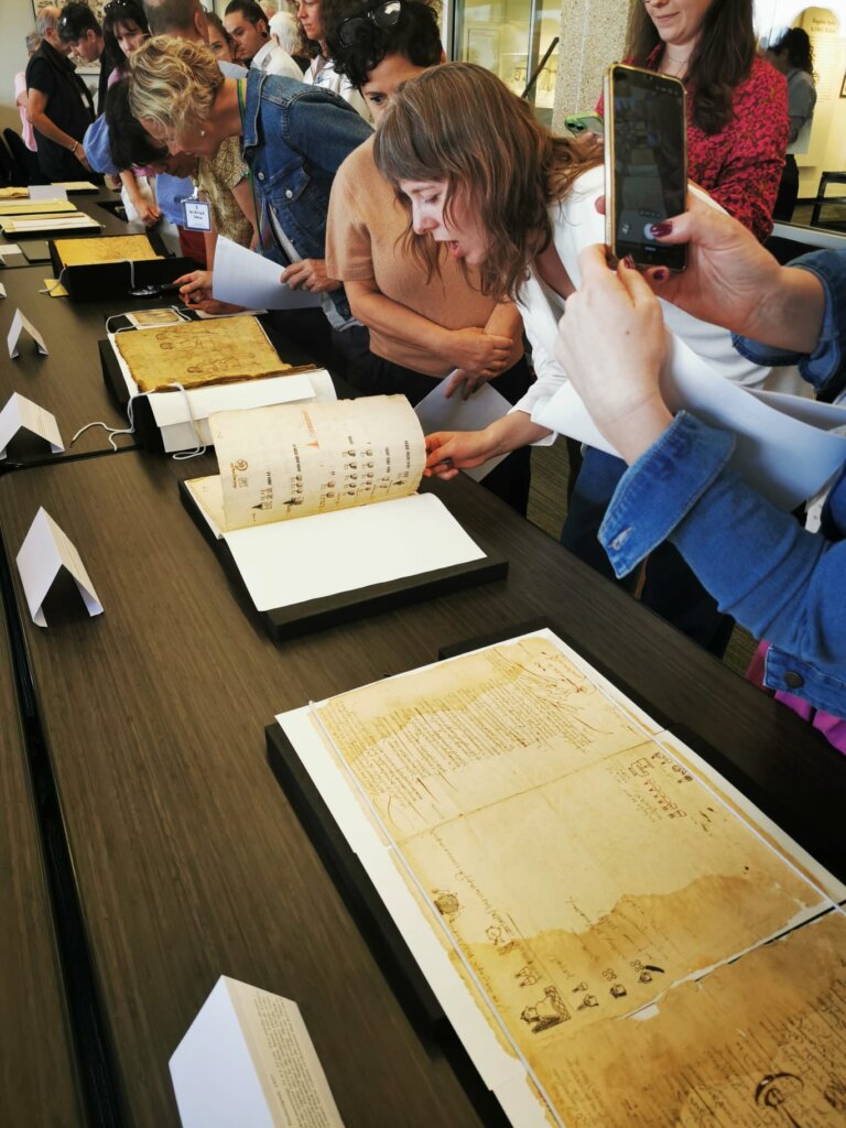 Julia Madajczak stands by a long table examining historical manuscripts together with other participants.